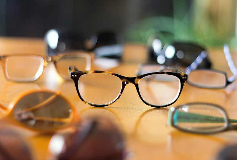 A collection of eyeglasses with various designs and colors displayed on a table.