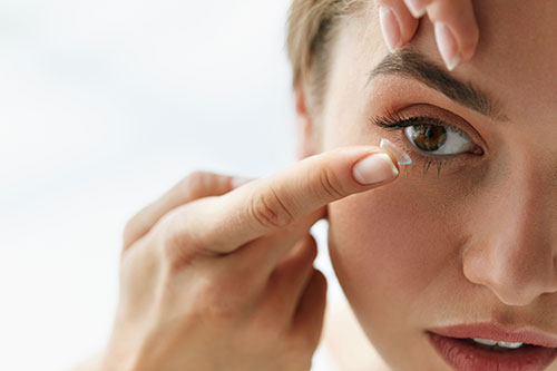 A close-up of a woman s face with her eyes closed, receiving an eye treatment or makeup application.