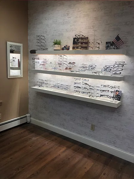 An optical store display with various eyeglass frames and a wooden wall in the background.